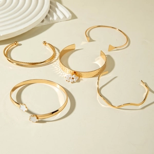 Détail d'un ensemble de 5 bracelets dorés avec breloques fleurs et perles