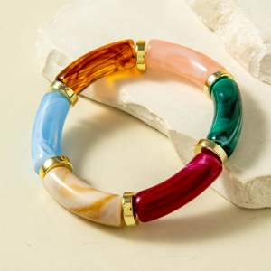 Colorful resin bamboo joint bracelet with gold spacers on natural stone background