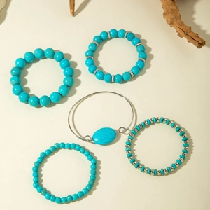 Five-piece bohemian turquoise bead bracelet set with silver metal accents on rustic wood