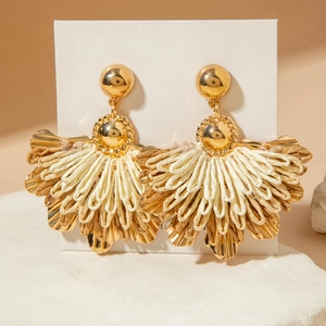 Close-up of bohemian fan-shaped raffia earrings with golden metal leaves detail