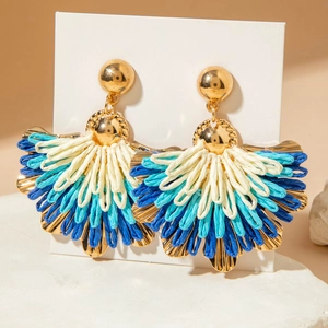 Detail of fan-shaped bohemian raffia tassel earrings with golden metal studs in trio colors