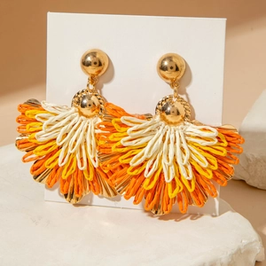 Bohemian fan-shaped raffia earrings in yellow and orange on a minimalist stone stand