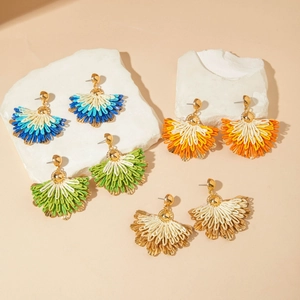 Bohemian raffia fan earrings in multiple colors displayed on white stone pedestals