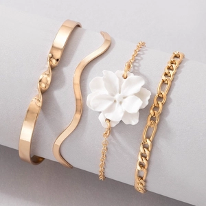 Detail of 4-piece gold jewelry set with camellia flower charm and multilayered bracelets