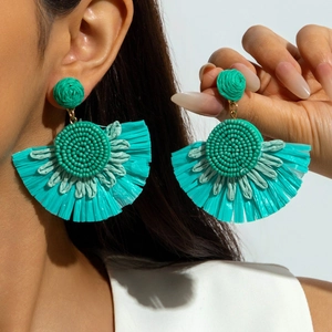 Close-up of bohemian fan-shaped turquoise raffia earrings featuring intricate bead embroidery