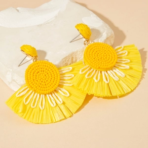 Detailed texture of yellow fan-shaped raffia flower earrings on a white stone pedestal