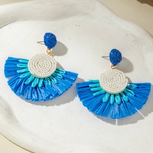 Macro view of blue raffia fan earrings featuring white bead centers and woven texture