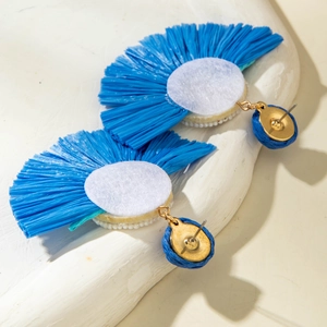 Detail view of blue raffia fan-shaped earrings with woven fabric and gold metal studs