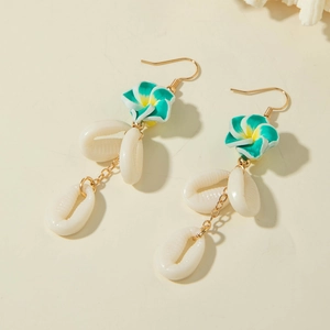 Detail of beach style earrings with yellow frangipani flower and three white seashells