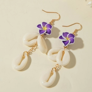 Detail view of purple plumeria earrings with three hanging white shells and golden hooks