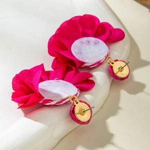 Close-up of rose red pleated fabric flower earrings with polished golden stud base