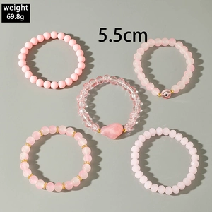 Detail view of 5-piece pink beaded bracelet set with heart charm and evil eye beads