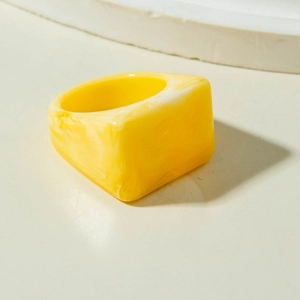 Vista detallada de anillo cuadrado de resina con textura de mármol amarillo y blanco liso