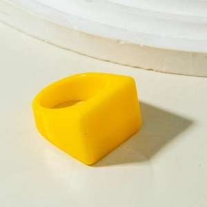 Primer plano de un anillo de acrílico grueso amarillo sobre base geométrica