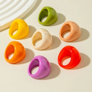 Set de siete anillos de resina de estilo pop art colorido sobre un fondo beige neutro