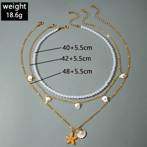 Detailed view of layered pearl necklaces with starfish and shell pendants in gold finish