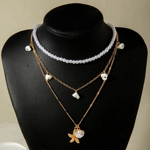 Close-up of layered necklace with pearls and starfish shell pendants on a black mannequin