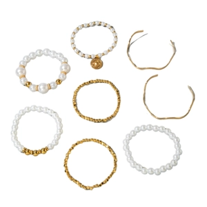 Multi-layer gold bracelet set with pearls, beads and gold coins on a white background