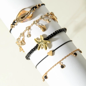 Five-piece bohemian anklet set with starfish, shells, and beads on a display stand