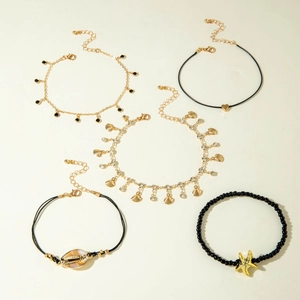 Five-piece Bohemian anklet set with starfish, shell charms and black beads on light background
