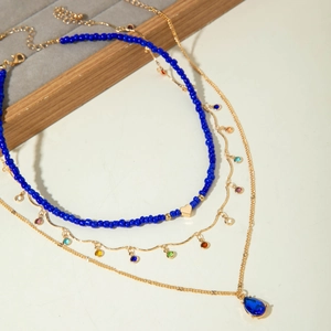 Three-layer gold necklace set featuring blue teardrop crystal and heart-shaped pendants