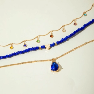 Three-piece gold chain set with blue teardrop gemstone and beaded heart pendant