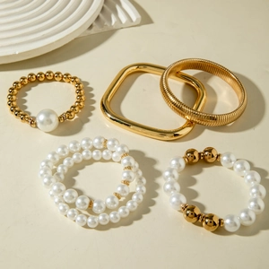Gold layered bracelet set featuring pearls and geometric bangles with bold aesthetic