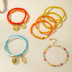 Detail of colorful bohemian beaded bracelets with gold shell and flower charms