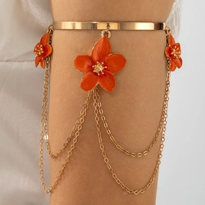 Detail of gold flower arm cuff with orange petals and cascading metal fringe tassels