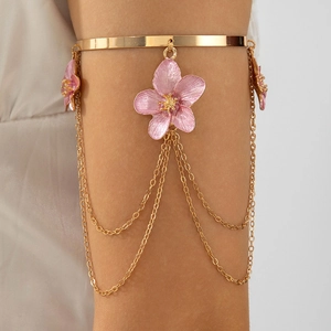 Close-up of golden arm cuff with pink flower pendant and layered tassel chains