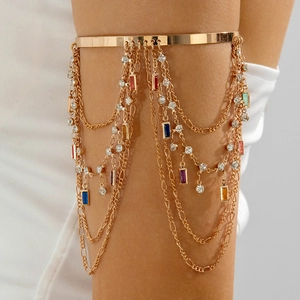 Λεπτομέρεια από boho χρυσό περιβραχιόνιο με πολύχρωμα κρύσταλλα και φούντες στρας