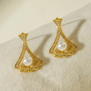 Macro shot of fan-shaped gold earrings with paved zircons and white round pearls