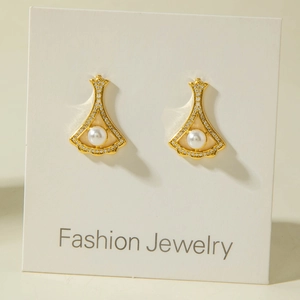 Close-up of fan-shaped gold earrings with sparkling crystals and a central white pearl
