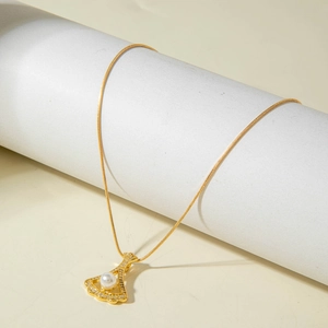 Close-up of golden snake chain necklace with pearl and crystal fan-shaped pendant