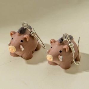 Close-up of 3D miniature wild boar earrings with realistic brown texture and metal hooks