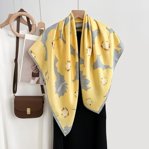 Élégant foulard carré en soie jaune à imprimé floral gris sur une robe noire