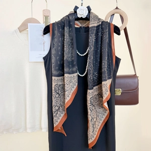 Elegant paisley print long silk scarf in black and orange paired with a black dress