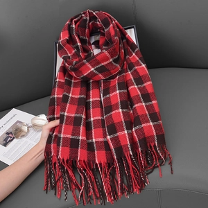 Classic red and black checkered knit scarf with long tassels on a dark leather background