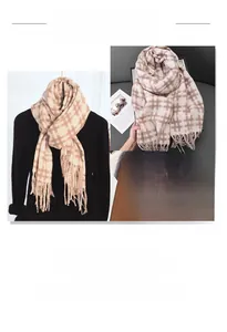 Detailed macro view of soft plaid tassel scarf texture with hand showing fabric thickness
