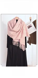 Detail of pink plaid cashmere-feel scarf with long tassels draped on a mannequin