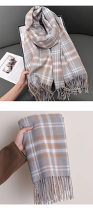 Detail of grey plaid scarf with orange stripes featuring long fringe and soft texture