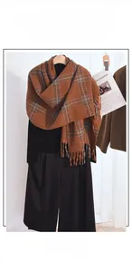 Close-up of caramel and brown plaid scarf featuring thick cashmere-like texture and tassels