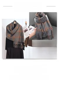 Detailed view of grey and orange plaid scarf with fringe trim and thick knit texture