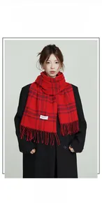 Detail of red and black plaid cashmere-like scarf with soft fringes on black coat