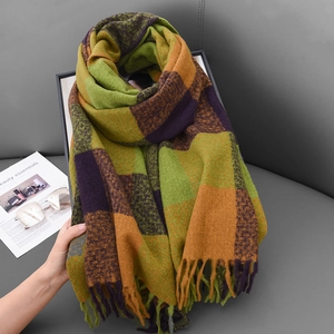 Winter plaid scarf with tassels in ginger and olive tones on a grey surface