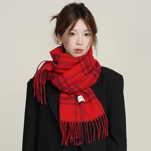 Plaid red and black cashmere-like scarf with fringe on a black coat studio shot
