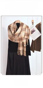 Detail of soft cashmere-like texture and tassel fringe on beige plaid winter scarf