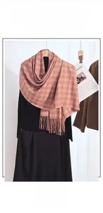 Detail of pink and brown plaid cashmere scarf with handmade fringe on a winter outfit