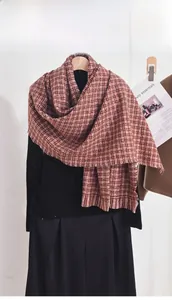 Détail d'une écharpe douce à motif pied-de-poule marron rouge sur un pull à col roulé