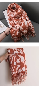 Détail d'une écharpe fleurie orange en imitation cachemire avec de douces franges